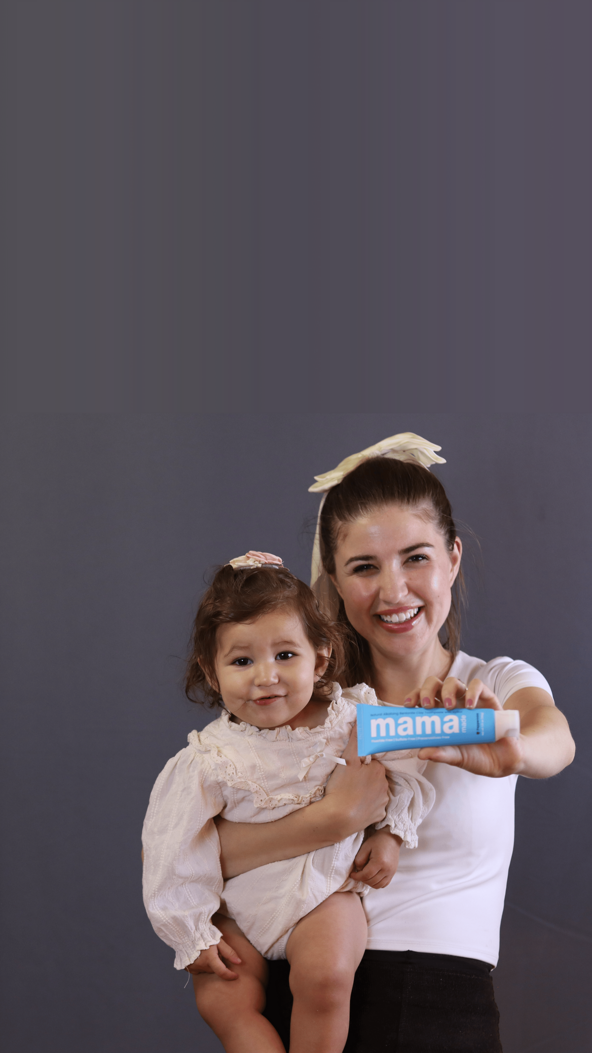 Woman carrying baby and holding the best bentonite clay toothpaste. Fluoride-free and SLS-free and Chemical-free, 100% natural bentonite clay toothpaste
